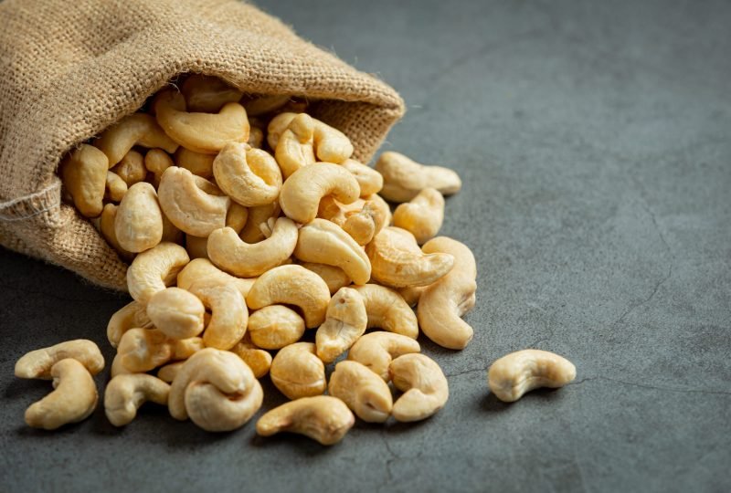 Raw cashews nuts in bag on dark background